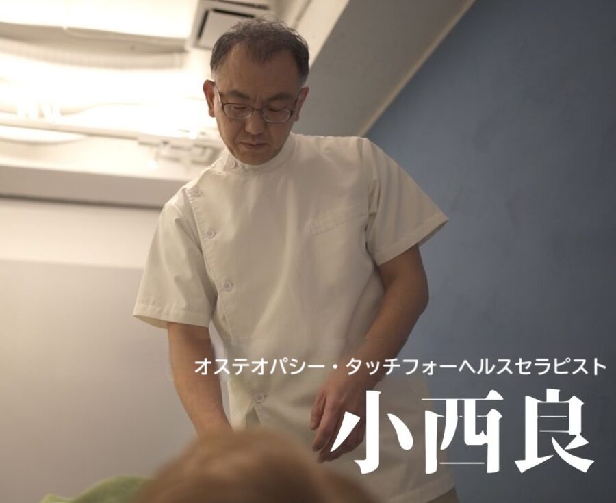 白衣で施術する小西良。オステオパシー・タッチフォーヘルスセラピスト